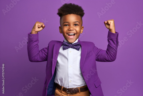 African American boy dressed stylish clothes celebrate success raise hands fists isolated on purple color background
