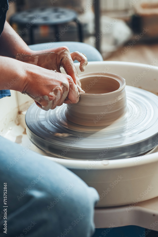 The female hands of a potter model a clay product on a wheel. Pottery craft, shaping a clay product, weekend activity The female hands of a potter model a clay product on a wheel. Pottery craft, shaping a clay product, weekend activity