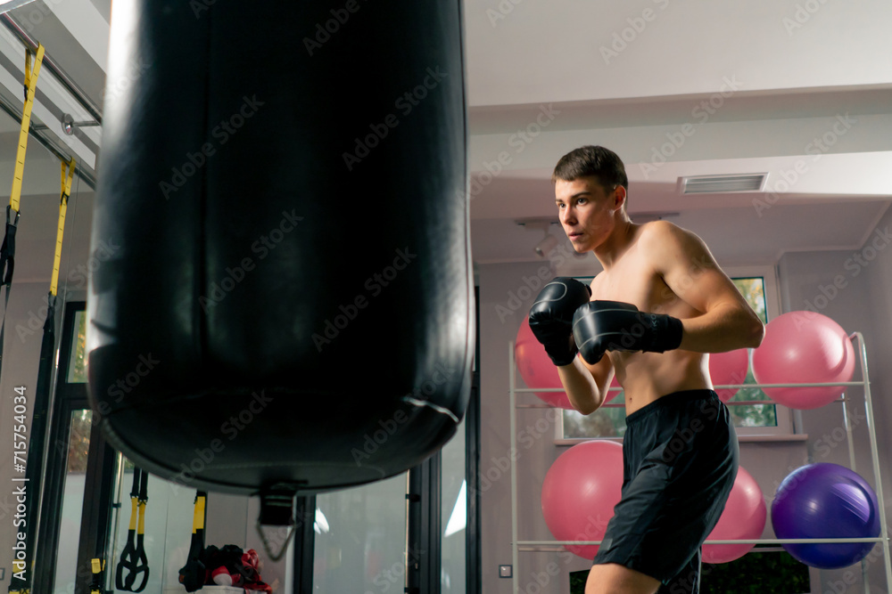 a boxer concentrates training in the gym in boxing gloves hitting a punching bag strength exercises