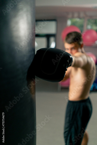 a boxer concentrates training in the gym in boxing gloves hitting a punching bag strength exercises © Guys Who Shoot