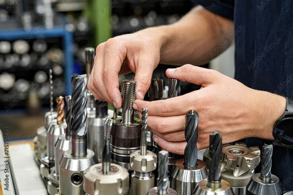 A worker inspects and selects a drill to work on a cnc milling machine. A worker inspects and selects a drill to work on a cnc milling machine.