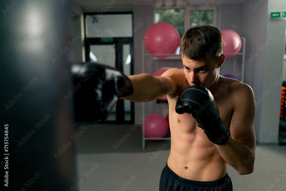 a boxer concentrates training in the gym in boxing gloves hitting a punching bag strength exercises