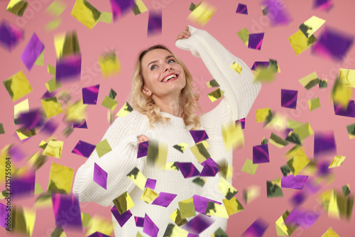 Happy woman under falling confetti on pink background