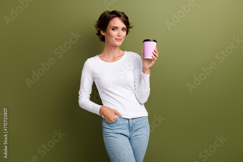 Photo portrait of pretty young girl hold paper cup enjoy coffee pause dressed stylish white outfit isolated on khaki color background