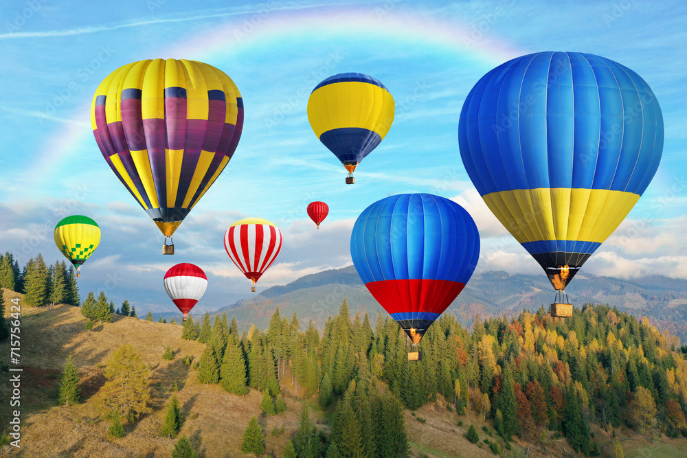 Fototapeta premium Bright hot air balloons flying in sky with rainbow over mountain