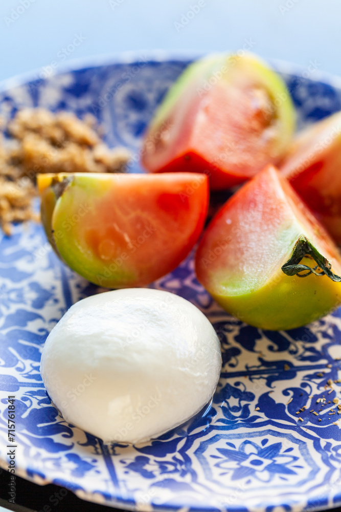 pomodori affettati crudi e mozzarella su piatto decorato con motivo blu, caprese italiana pomodori affettati crudi e mozzarella su piatto decorato con motivo blu, caprese italiana