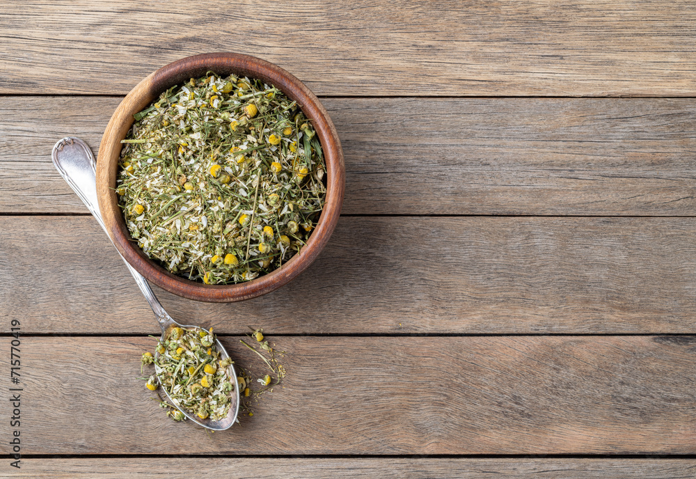 Chamomile dried tea leaves and flowers on a bowl over wooden table with copy space Chamomile dried tea leaves and flowers on a bowl over wooden table with copy space