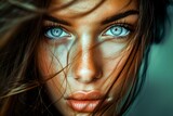 Close-up portrait of a young woman with striking blue eyes and windswept brown hair, expressing beauty and emotion.