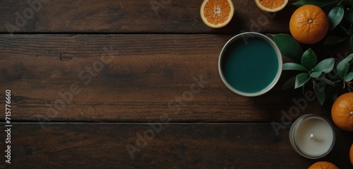  a wooden table topped with oranges and a cup of green liquid next to a couple of oranges on top of a wooden table next to a candle holder.