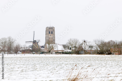 View of Goedereede in The Netherlands with its Tower and Windmill in the snow during winter. photo