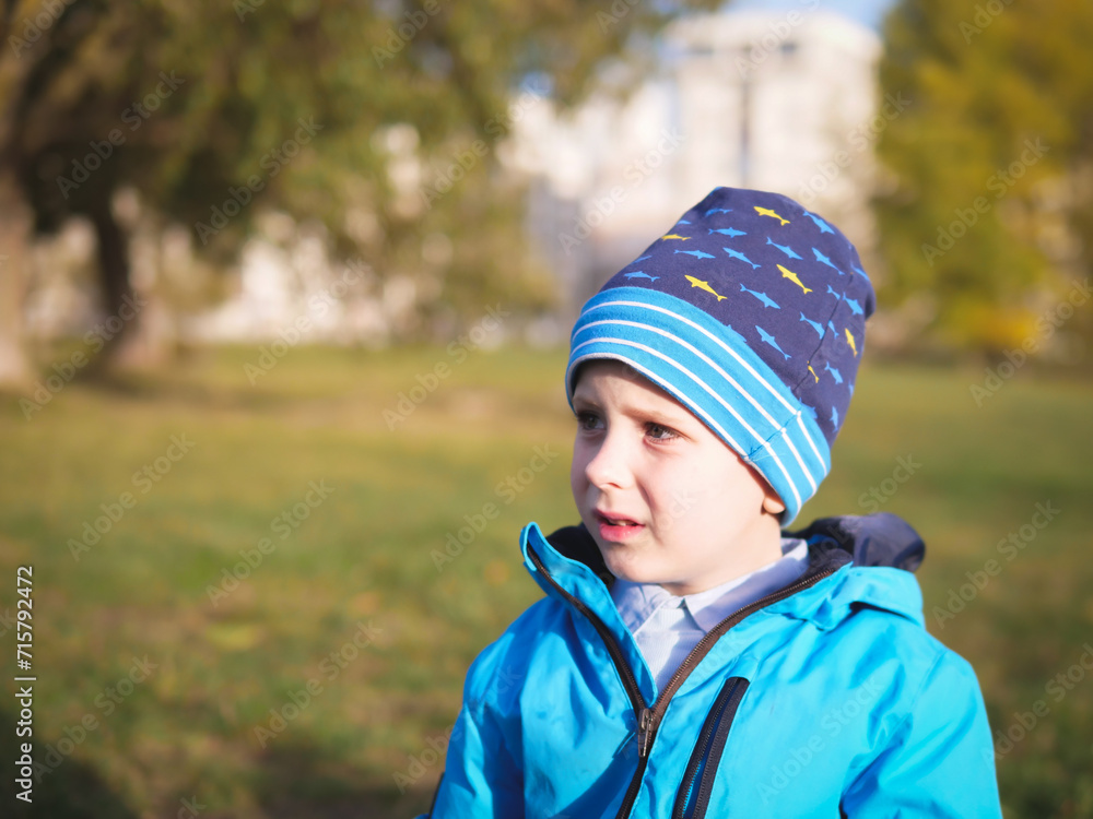Little Slavic boy child portrait in spring or autumn on the lawn in a city park Little Slavic boy child portrait in spring or autumn on the lawn in a city park