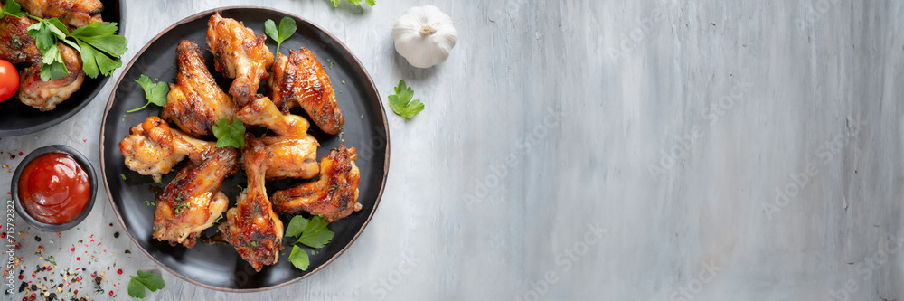 Grilled chicken wings with tomato sauce and garlic on gray background. Top view, copy space