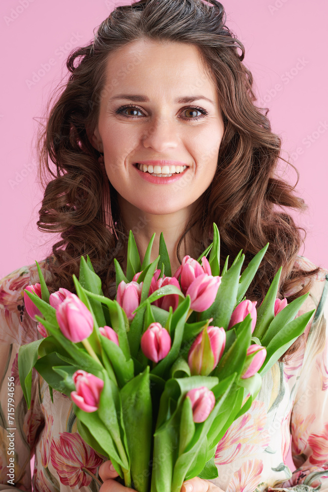 Portrait of happy stylish woman in floral dress on pink