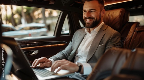 Handsome businessman working on laptop computer while sitting in luxury car. photo