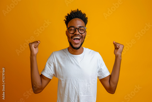 Happy black person , excited young African American male, cheerful black man, screaming in amazement. Surprised face, isolated on yellow background with copy space