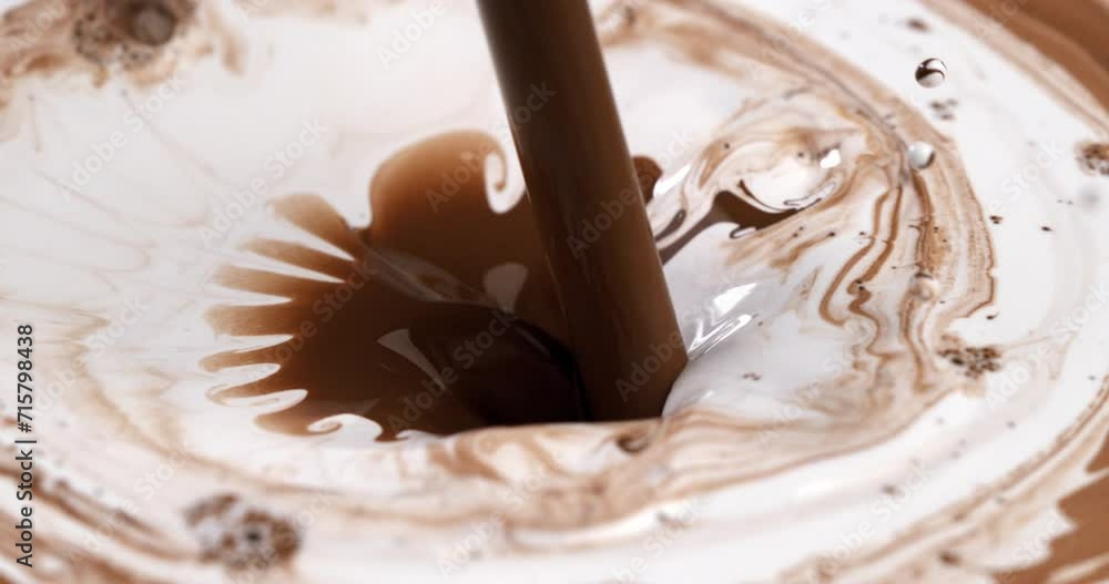 Super slow motion macro of cocoa liquid chocolate is poured in fresh organic bio milk with splashing white drops at 1000 fps.