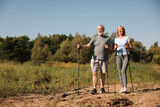 Senior couple with poles for Nordic walking outdoors on sunny day