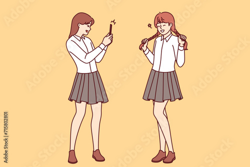 Teenage girls had photo shoot in school uniforms, posing for avatar for mobile application on social network. Female student takes photo friend on smartphone to post portrait on personal internet blog