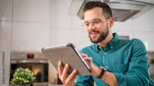 One young adult caucasian man work use digital tablet online at home photo