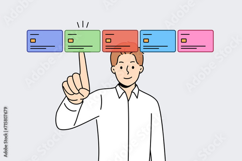 Man selects credit card on virtual screen, wanting to make cashless payments through web banking application. Obtaining new credit card using modern technologies to ensure secure online shopping