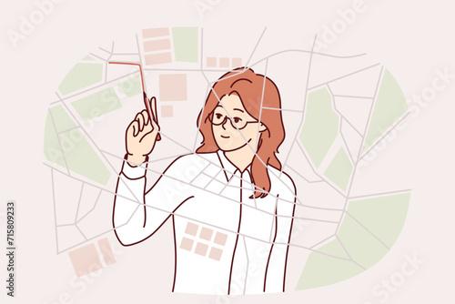 Woman logistician draws up route for delivery service vehicles by drawing lines on city map. Girl works as logistician in transportation company and develops shortest routes for courier transport