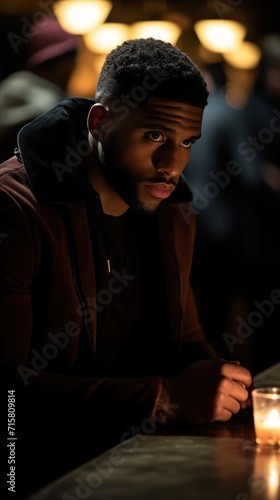 Serious portrait of a young African-American man sitting at a bar counter, deep in thought, contemplative expression