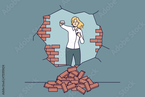 Strong woman breaks down barriers to business success by making hole in brick wall. Ambitious business lady moves forward eliminating troubles and wanting to develop in difficult situation.