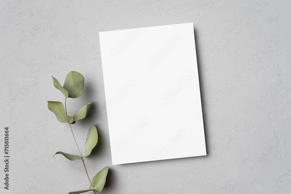 Blank paper invitation or greeting card mockup with eucalyptus twig decor on grey background Blank paper invitation or greeting card mockup with eucalyptus twig decor on grey background