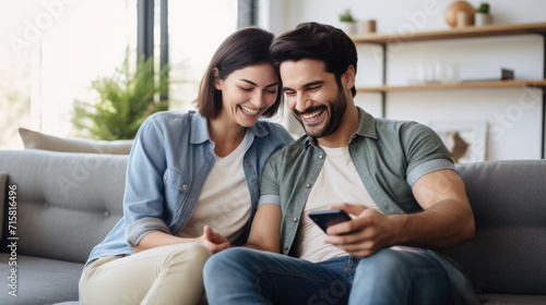 Smiling man and woman sitting closely together on a couch, looking at a tablet screen, in a moment of shared happiness and connection.