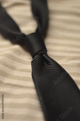 close up of a black tie on beige background