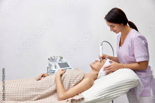 cosmetologist doing peeling procedure for female client in beauty salon photo