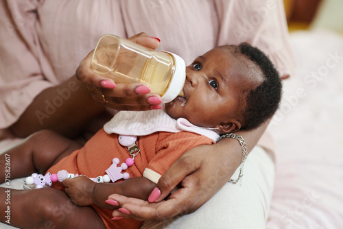 Black woman feeding her newborn baby girl with formula photo