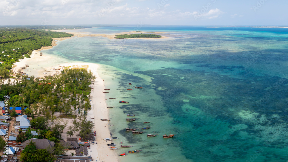 Aerial view of the fishing boats on tropical sea coast with sandy beach.Summer travel in Zanzibar, Africa. Top view of boats, yachts and clear blue water.