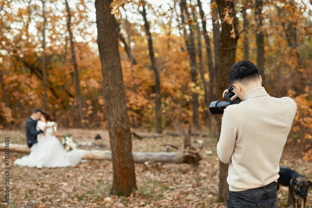 Professional wedding photographer taking pictures of the bride and groom in nature in autumn Professional wedding photographer taking pictures of the bride and groom in nature in autumn