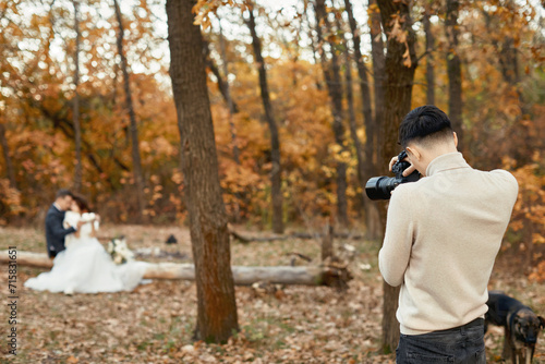 Professional wedding photographer taking pictures of the bride and groom in nature in autumn © producer