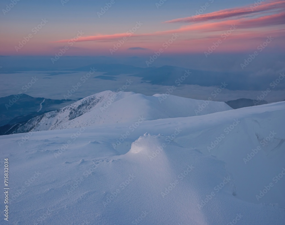 The first sunlight on the mountains shines through the fog and clouds. Snow-covered hills with dramatic scenery. Colorful sunrise. Ridge of the Low Tatras, Slovakia