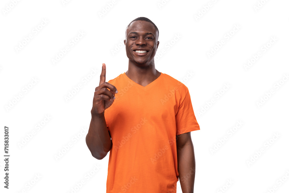young positive happy american man in orange t-shirt points his finger at the presence of interesting news and advertising young positive happy american man in orange t-shirt points his finger at the presence of interesting news and advertising