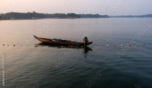 A fisherman is fishing in Kaptai Lake in the afternoon. The scene is amazing. photo