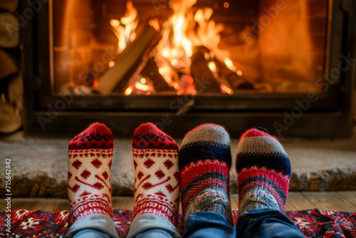 vue sur des paires de pieds avec des chaussettes d'hiver dans le style de noël, feu de cheminée  en arrière plan photo