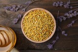 Fresh bee pollen granules and lavender on wooden table, flat lay
