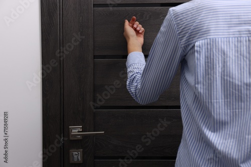 Woman knocking on door indoors, closeup. Space for text photo