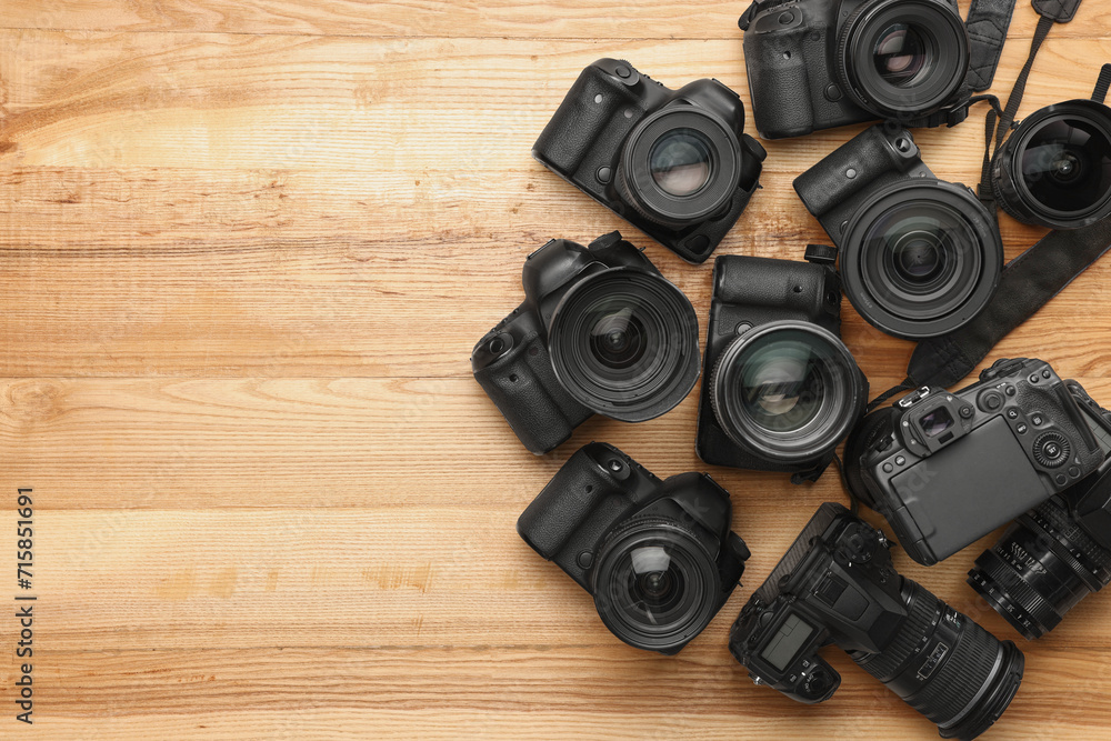 Modern different cameras on wooden table, flat lay. Space for text