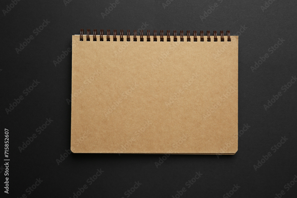 One notebook on black background, top view One notebook on black background, top view