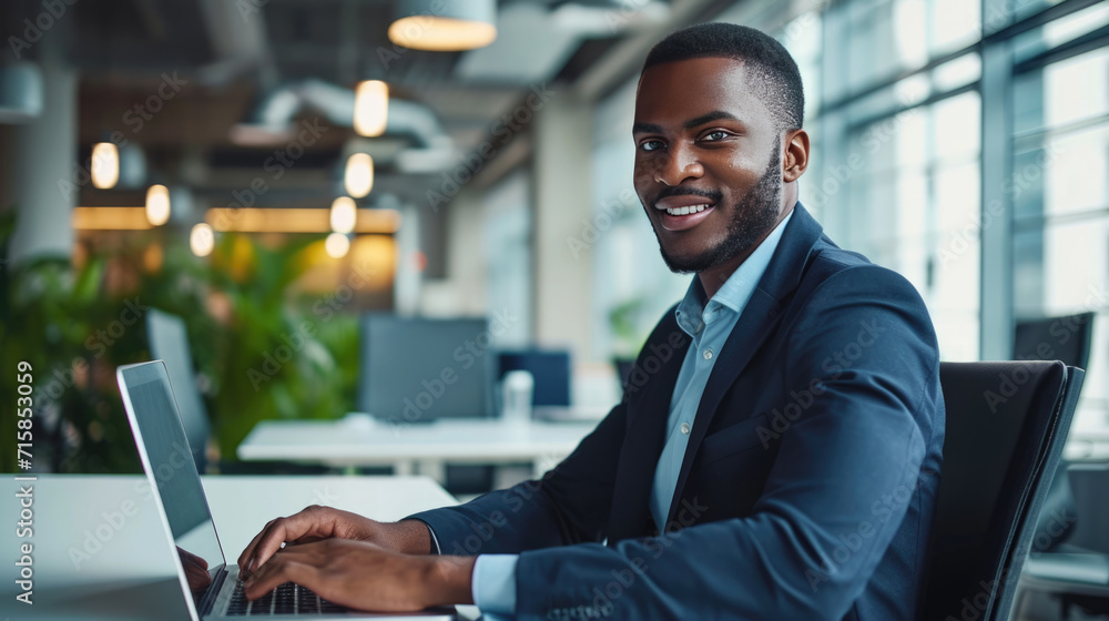 Fototapeta premium Man smiling while working on a laptop in a modern office environment