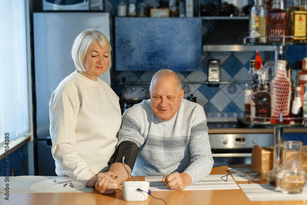 An elderly woman measures her husband's blood pressure and pulse. An elderly woman measures her husband's blood pressure and pulse.