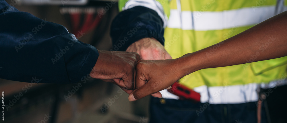 Team engineers and foreman stack hand and shake hands to show success at inverter solar panel room. Worker industry join hand for collaboration.