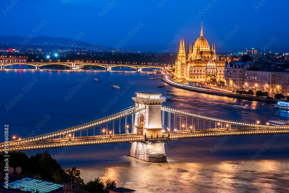 The picturesque landscape of the Parliament and the famous Szechenyi chain bridge over the Danube in the light of lamps in Budapest, Hungary.
