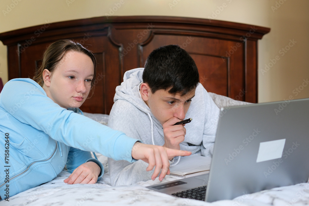 Two caucasian children watching something funny on laptop. Attractive brunette boy pointing his hand on screen. Pretty little girl laughing from what she see on computer. High quality Two caucasian children watching something funny on laptop. Attractive brunette boy pointing his hand on screen. Pretty little girl laughing from what she see on computer. High quality