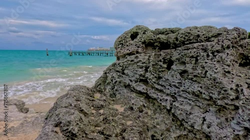 Vista del mar caribe con agua turquesa sobre una isla de rocas y un muelle de madera de fondo photo
