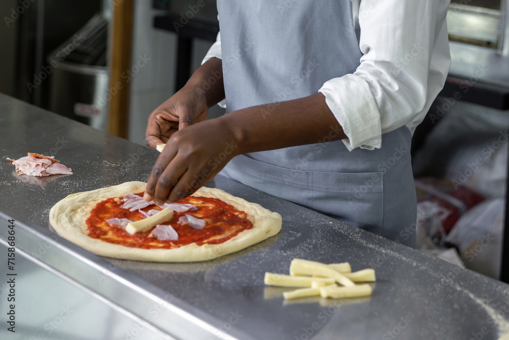 Female pizzeria cook preparing pizza in the kitchen